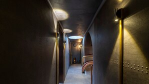 A narrow, industrial-style hallway with metallic walls, a curved staircase, and a skylight. - Unique lodging, steampunk vibe - 2 guests (Raon-aux-Bois)