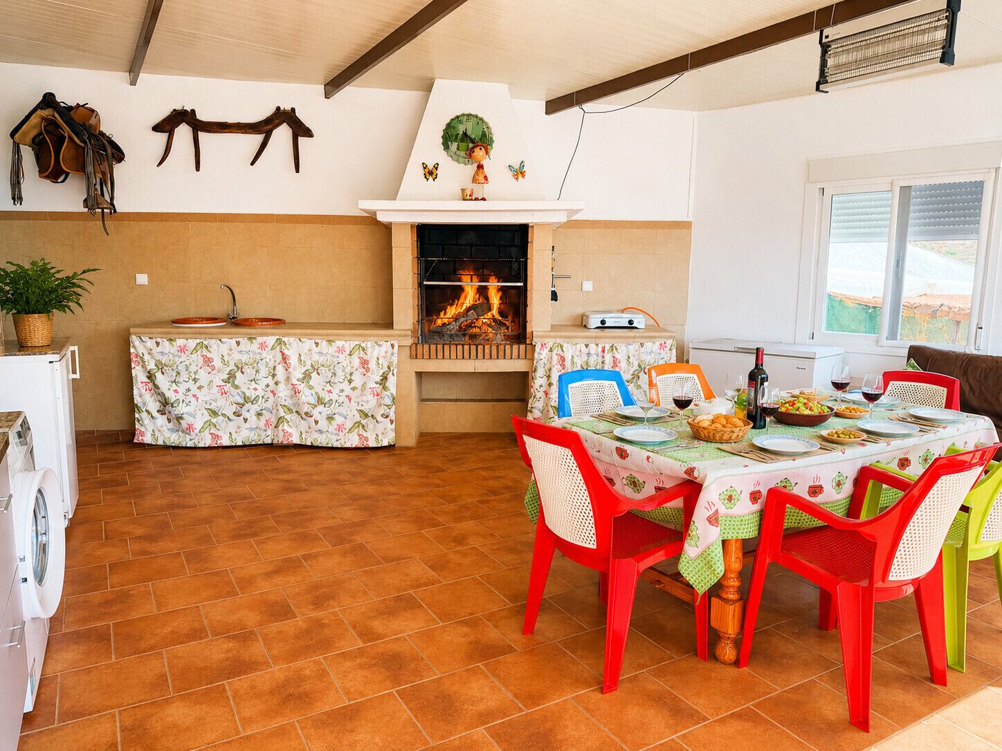A kitchen with a fireplace, a dining table set for four, and a washing machine.