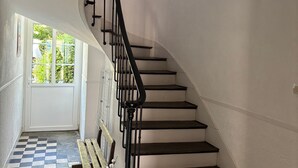 A staircase with a black handrail and white walls, leading to a door with a checkered floor. - Welcoming gîte near Verdun - 7 guests (Brainville)
