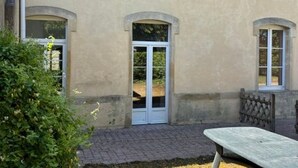 A building with a beige exterior, arched windows, and a paved courtyard. - Welcoming gîte near Verdun - 7 guests (Brainville)