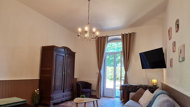 A living room with a sofa, a television, a wooden cabinet, a chair, and a small table. - Welcoming gîte near Verdun - 7 guests (Brainville)