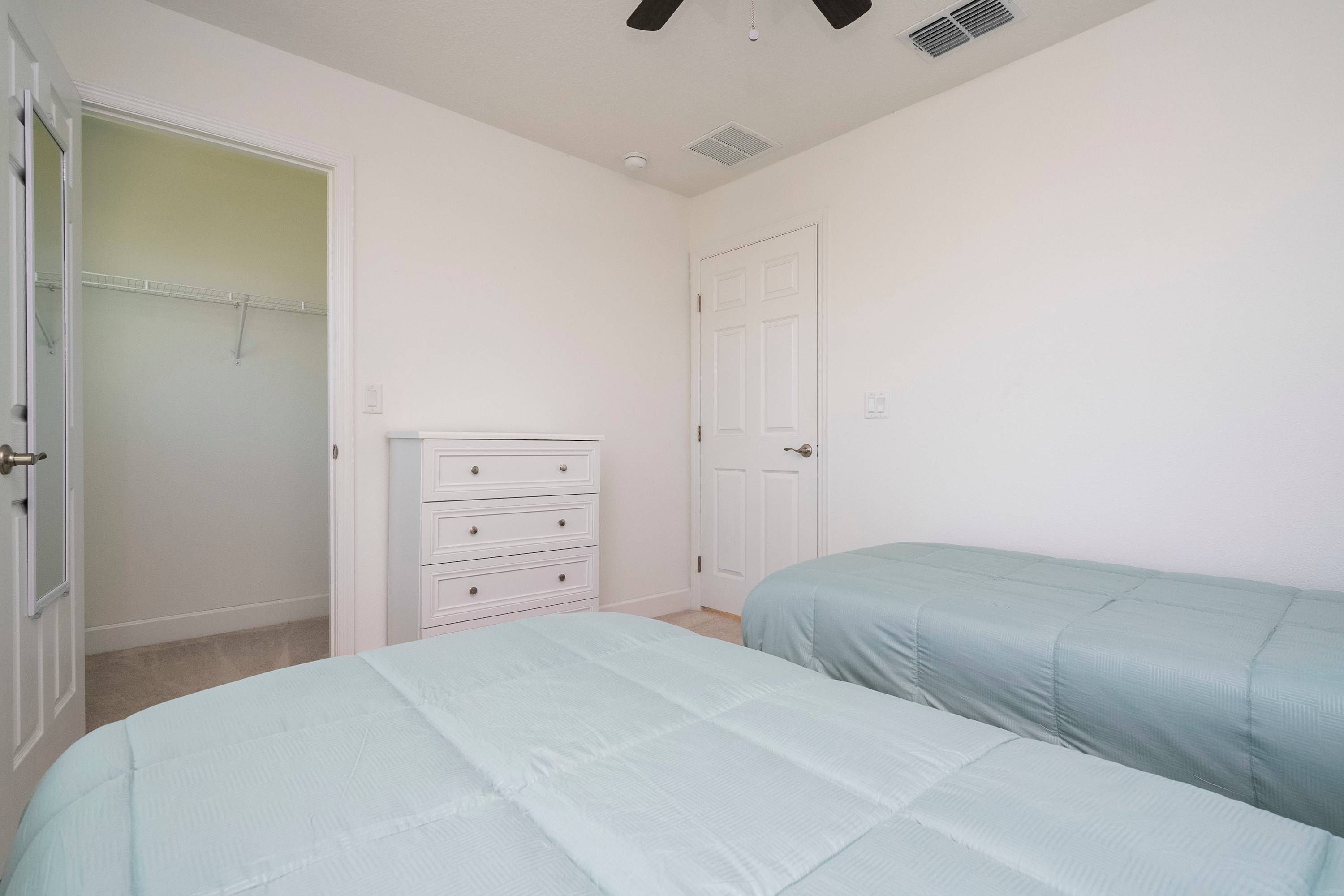 Une chambre avec deux lits, un placard et une porte.