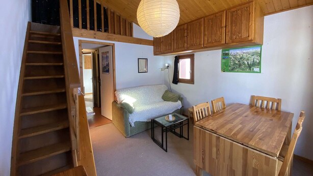A wooden interior with a bed, a dining table, and a staircase. - Studio at the foot of the slopes - 5 guests (Arêches-Beaufort)
