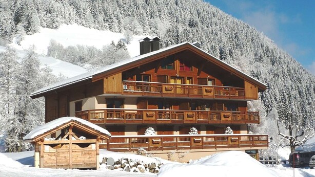 A multi-story wooden lodge with balconies, set against a snowy mountain backdrop. - Spacious apartment - 8 guests (Arêches-Beaufort)