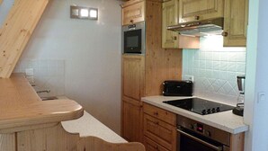 A compact kitchen with wooden cabinets, a built-in oven, a toaster, and a sink. - Spacious apartment - 8 guests (Arêches-Beaufort)