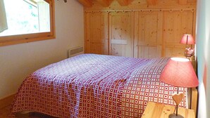 A bedroom with a bed, a window, a lamp, and wooden walls. - Spacious apartment - 8 guests (Arêches-Beaufort)