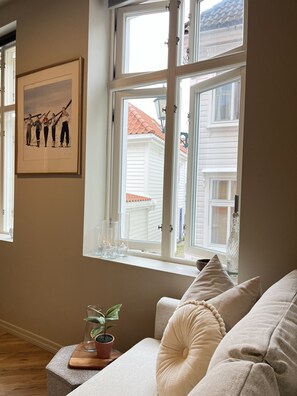 A room with a window, a framed picture on the wall, a potted plant, and a beige sofa. - Central apartment by Nøstet, Bergen (Bergen)