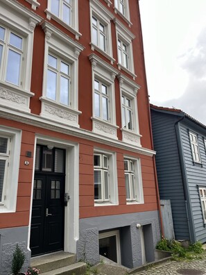 En byggnad med flera våningar, en röd fasad, vita fönsterramar och en svart ytterdörr.