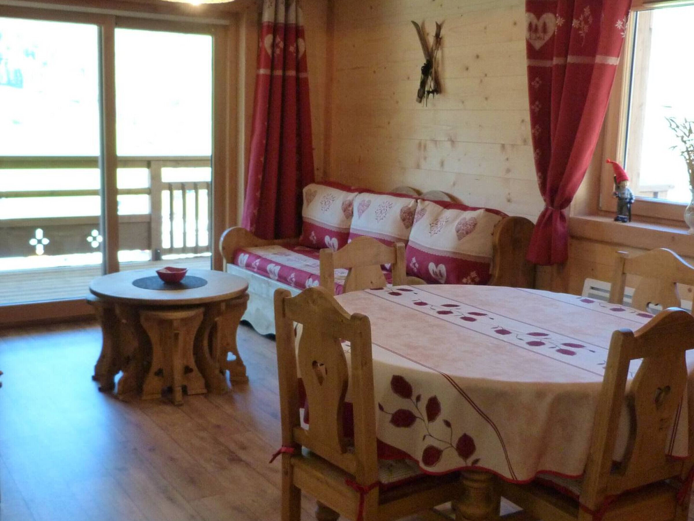 Une pièce chaleureuse avec une table en bois, des chaises, un canapé et une fenêtre avec des rideaux.