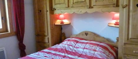 A single bed with a patterned bedspread, wooden headboard, and two bedside lamps.