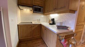 Une cuisine avec des meubles de rangement en bois, un four à micro-ondes, un évier et une machine à café.