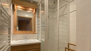 Une salle de bain avec un meuble-lavabo en bois, un évier, un miroir et une cabine de douche en verre.