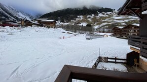 Een besneeuwd berglandschap met houten gebouwen, een skilift en een heldere lucht.