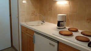 Een keuken met een spoelbak, een koffiezetapparaat en een fornuis.