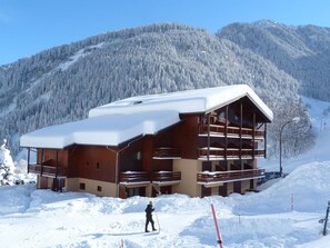 A multi-story wooden building with balconies, surrounded by snow-covered mountains. - Studio close to slopes - 5 guests (Arêches-Beaufort)