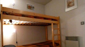 Een stapelbed met een ladder, een kussen, een wandlamp en een radiator.