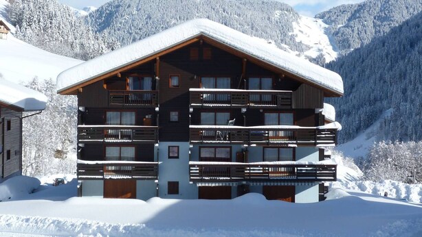 A multi-story wooden lodge with balconies, surrounded by snow-covered mountains. - Apartment at the foot of the slopes - 6 guests (Arêches-Beaufort)