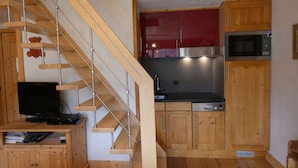 A modern kitchen with wooden cabinets, a stainless steel microwave, and a wooden staircase. - Apartment at the foot of the slopes - 6 guests (Arêches-Beaufort)