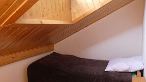 A small, single-bed room with a sloped ceiling and wooden beams. - Apartment at the foot of the slopes - 6 guests (Arêches-Beaufort)