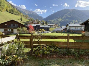 Ein ländliches Dorf mit Holzhäusern, einem Holzzaun und einer Bergkulisse.