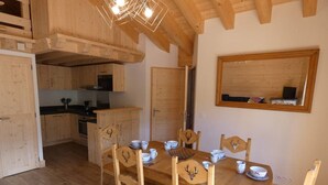 Uma sala de jantar de madeira com uma mesa posta para quatro pessoas, rodeada por cadeiras com detalhes de chifres.