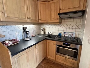 Eine Küche mit Holzausstattung, einer schwarzen Arbeitsplatte, einer Kaffeemaschine, einem Spülbecken und einem Backofen.