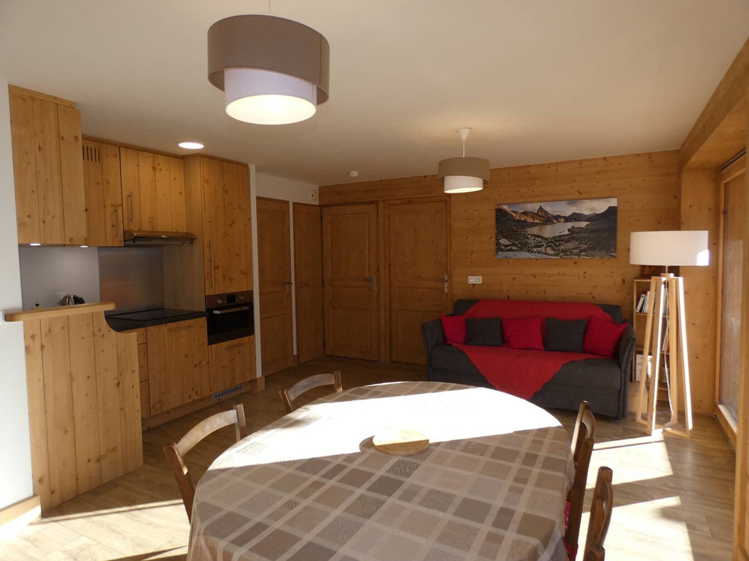 Ein Holzinterieur mit einem Esstisch, Stühlen, einer Couch und einem Bild an der Wand.