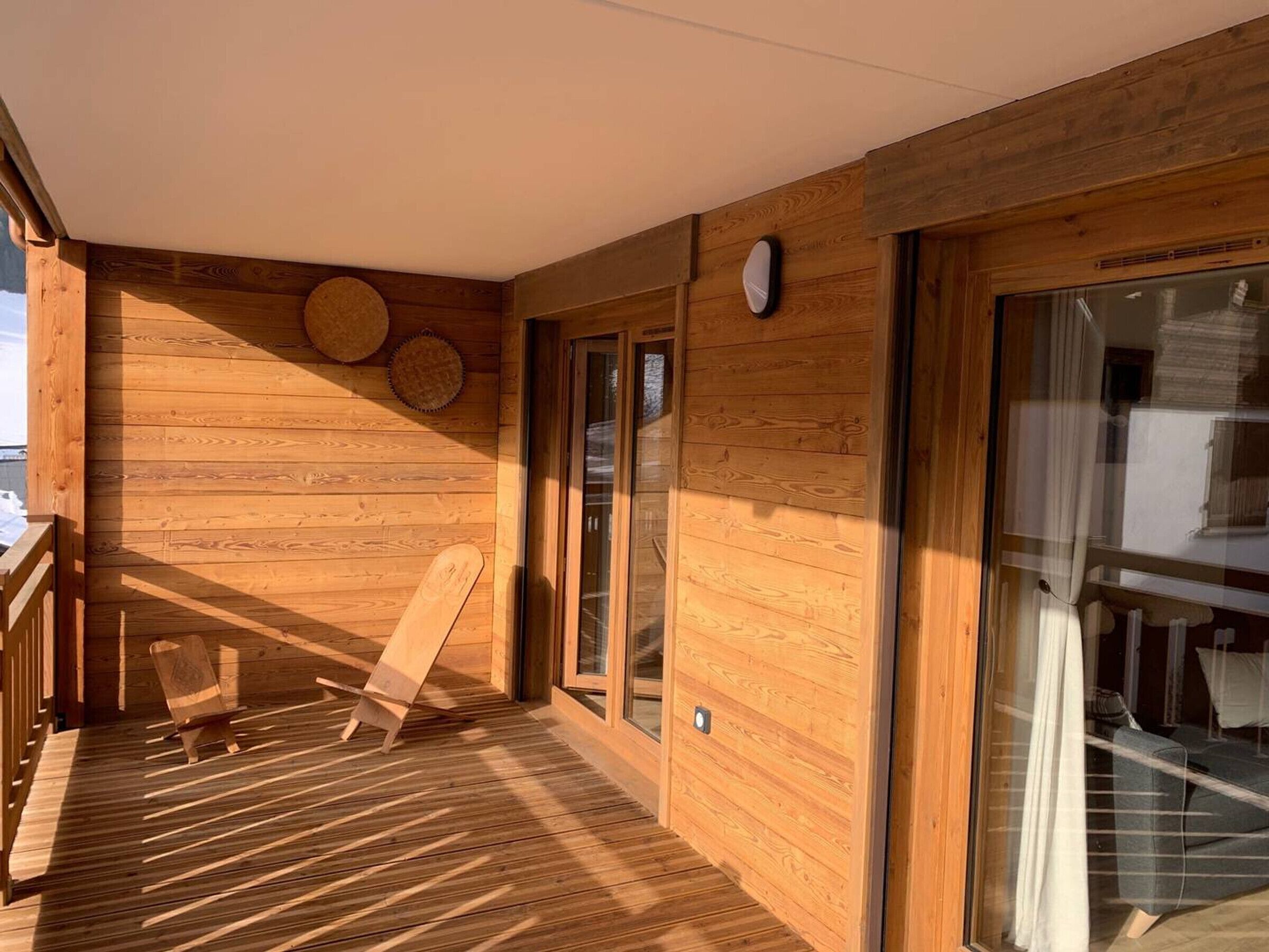 Ein Holzblockhaus-Innenraum mit einer Terrasse, einem Sessel und einem Bett.