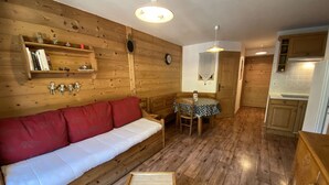 A wooden interior with a sofa, a dining table, and a small wooden chest. - Cozy apartment near shuttles - 4 guests (Arêches-Beaufort)