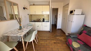 Un espacio habitable compacto con comedor, kitchenette y sofá.