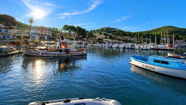 Un puerto deportivo con barcos amarrados, agua tranquila y edificios al fondo.