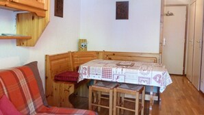 Ein gemütliches Zimmer mit einer hölzernen Bank, einem Tisch mit gemustertem Tuch und einem roten Karossofa.