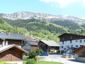 Ein Bergdorf mit traditionellen Holzhäusern, einem Restaurant und Blick auf die umliegenden Hügel.