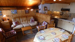 Ein gemütliches Blockhaus-Interieur mit Sofa, Esstisch, Holzschränken und einer Küchenzeile.