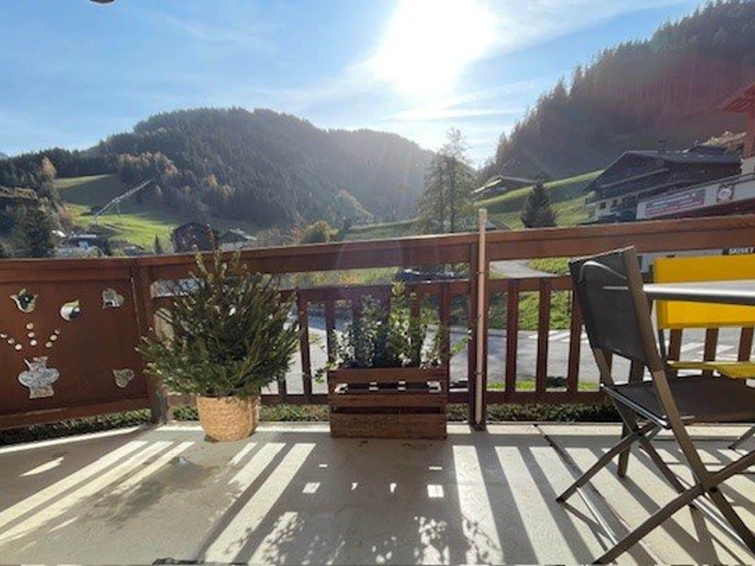 Un balcón con vista a un paisaje montañoso, una planta en maceta y una silla.