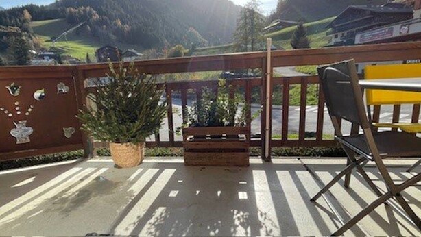 Een balkon met uitzicht op een berglandschap, een bloempot en een stoel.