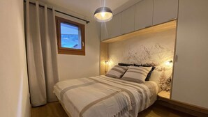 Een slaapkamer met een bed, een raam en een wandlamp.
