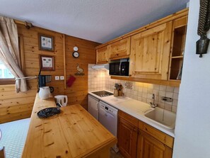A wooden cabin-style kitchen with a microwave, sink, and wooden cabinets.