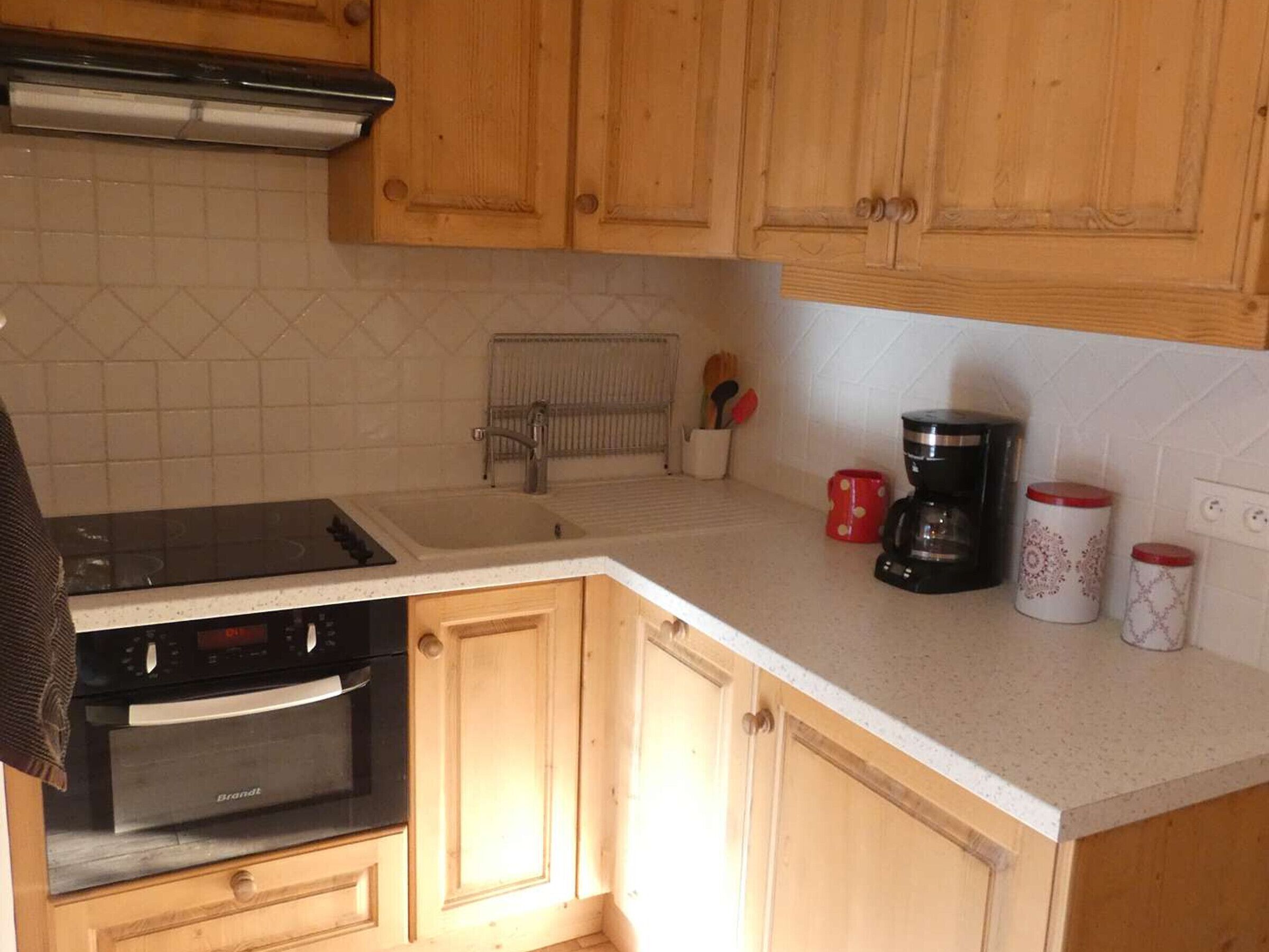 A kitchen with wooden cabinets, a stove, a sink, and a coffee maker.