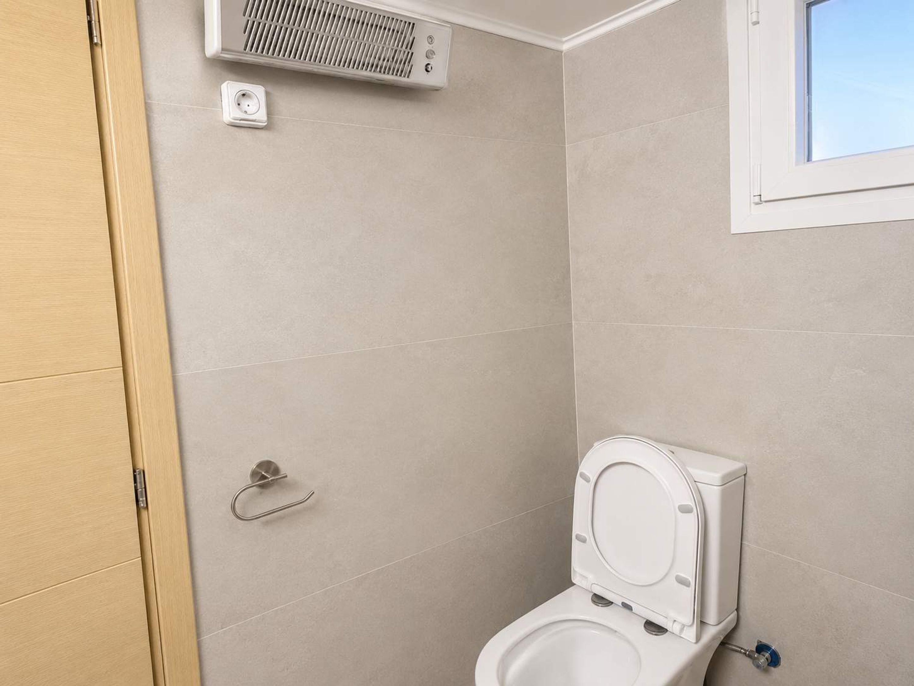 Un baño con inodoro, ducha y ventana.