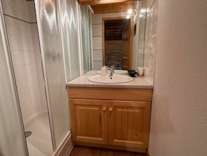 Ein Badezimmer mit einem Holztischchen, einem Waschbecken und einem Spiegel.