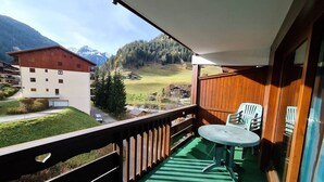 A balcony with a table and chairs, a view of a mountain, and a building in the background. - Apartment close to slopes - 4 guests (Arêches-Beaufort)
