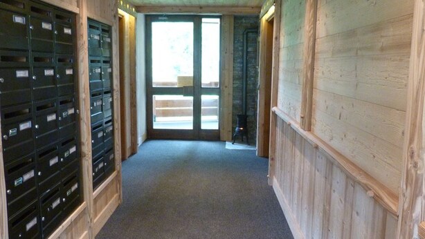 A hallway with wooden walls, a carpeted floor, and a set of mailboxes on the left. - Apartment close to slopes - 4 guests (Arêches-Beaufort)