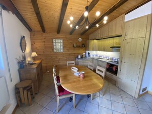 Ein Holzkamin mit Esstisch, Stühlen, einer Chandelier und einer Küchenzeile.