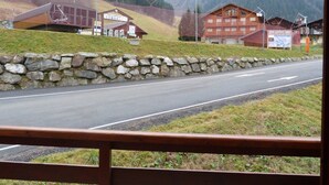 Uma estrada com um muro de pedra e edifícios ao fundo.