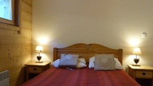 Ein Zimmer mit Holzwänden, einem Bett, zwei Nachttischen mit Lampen und einem Fenster.