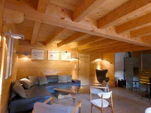 A cozy wooden interior with a sofa, chairs, and a dining table. - Spacious chalet with parking - 13 guests (Arêches-Beaufort)