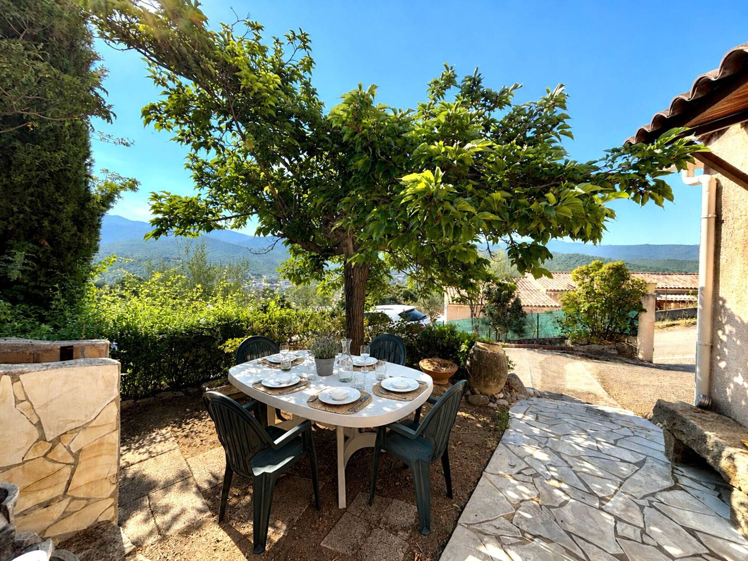 Un'area pranzo all'aperto con un tavolo imbandito per quattro persone, circondata dal verde e vista su dolci colline.