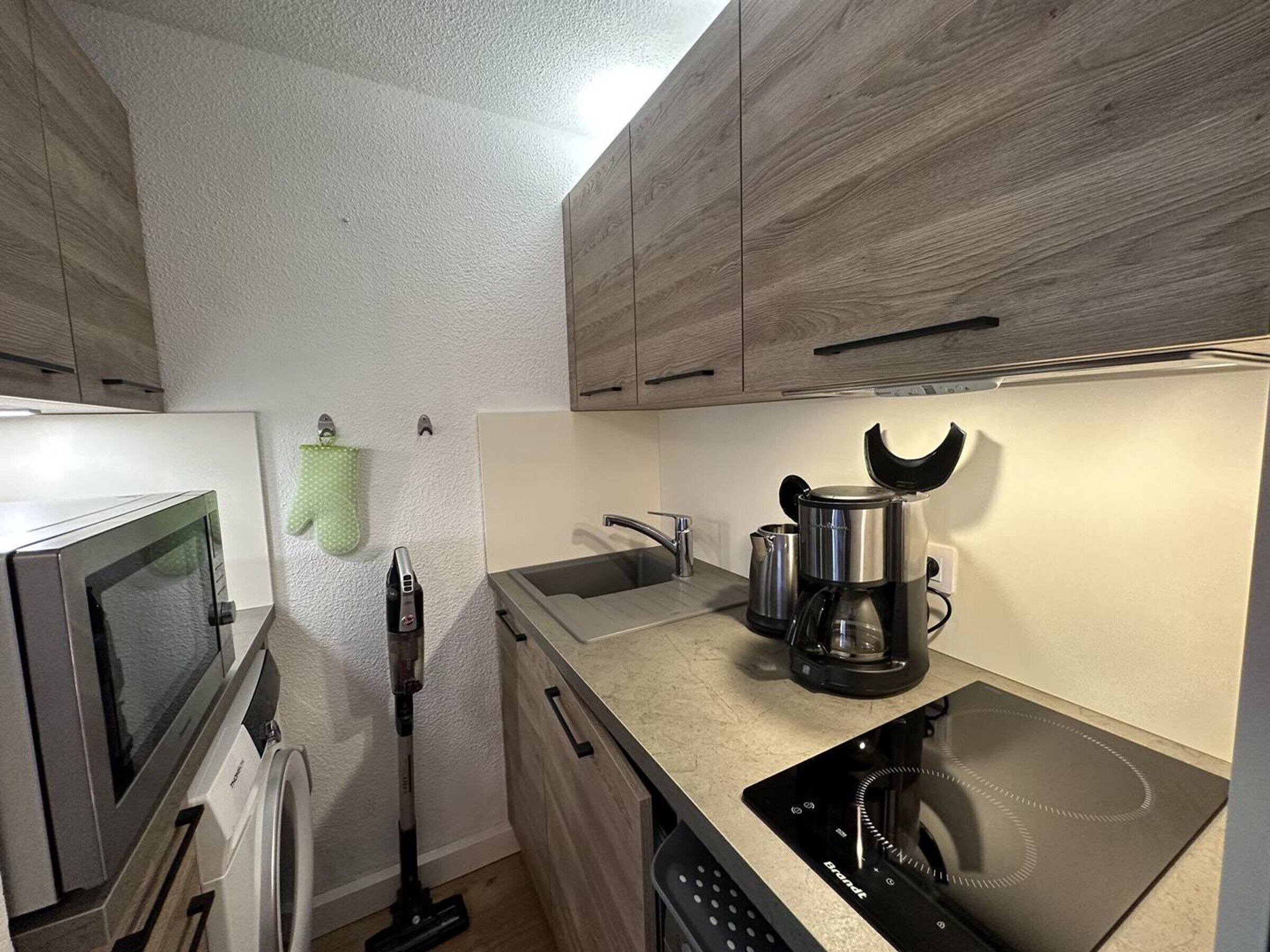 Et kompakt køkken med mikroovn, kaffemaskine og opvaskemaskine.