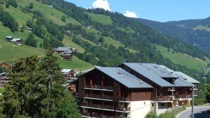 A mountain resort with wooden buildings, balconies, and a clear view of the surrounding hills. - Cozy apartment in village center - 4 guests (Arêches-Beaufort)